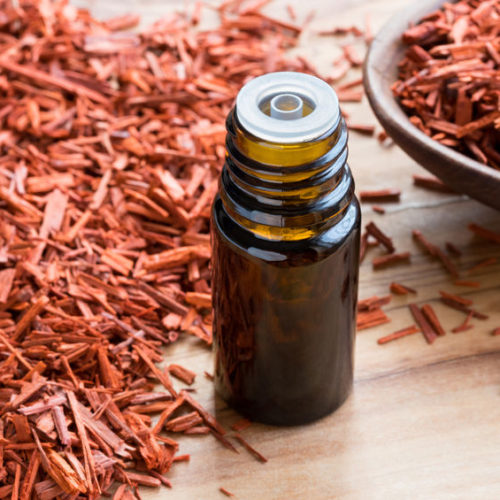 93543275 - a bottle of sandalwood essential oil on a wooden table, with sandalwood in the background